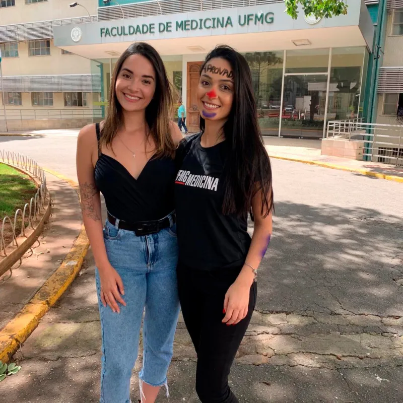 Bella Nazar com aluna aprovada em Medicina na UFMG, em frente à faculdade